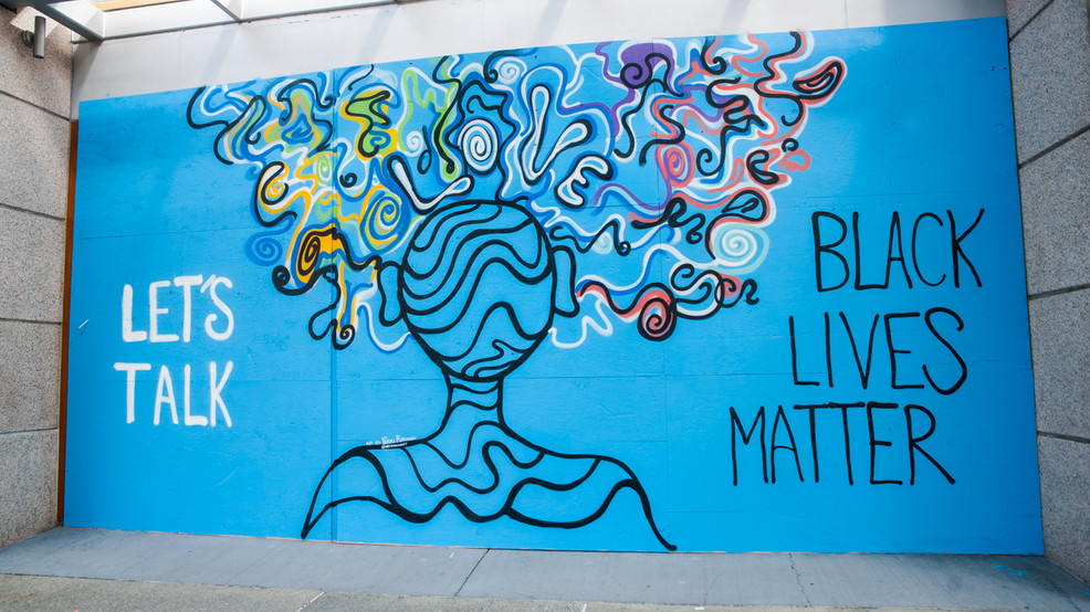 A Black Lives Matter mural by local Seattle artist Perri Rhoden. It says “Let’s Talk” on the left side, and “Black Lives Matter” on the right, with an abstract painting of a human silhouette in the middle.